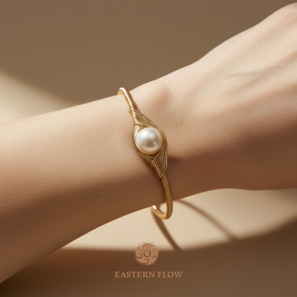Wrist shot of Metal-element gold pearl cuff bracelet, natural pearl energy talisman for executives, minimalist warm neutral backdrop